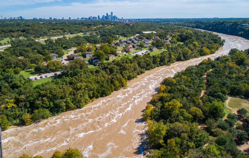 Austin Flooding aerial drone view from high above Colorado River and Red Bud Isle Flood waters  with Austin , Texas skyline in the far distance