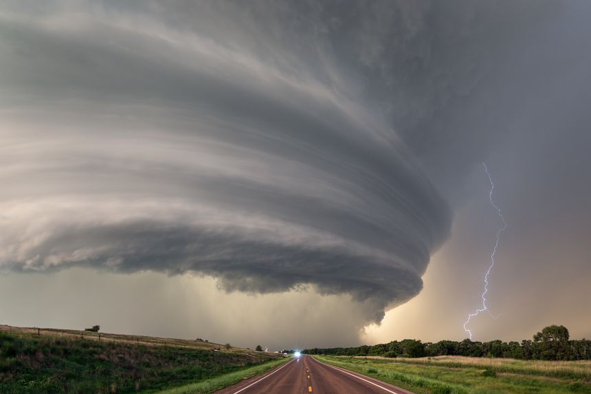 A powerful supercell thunderstorm with dramatic storm clouds and lightning over a highway in Nebraska. Severe weather concept.