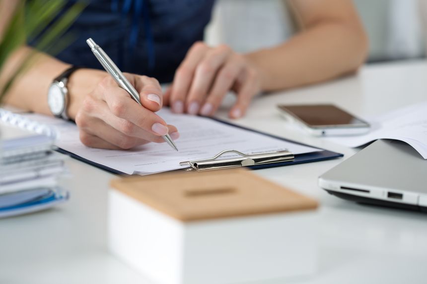 Close-up of female hands. Woman writing something sitting at her office