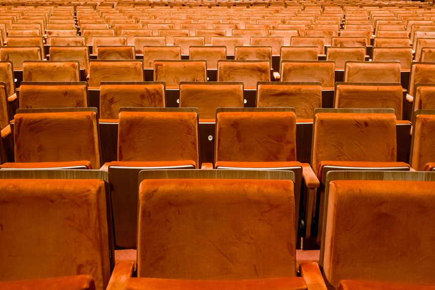 Rows of empty golden orange cushions theatre seats viewed from the side creating a repeating pattern