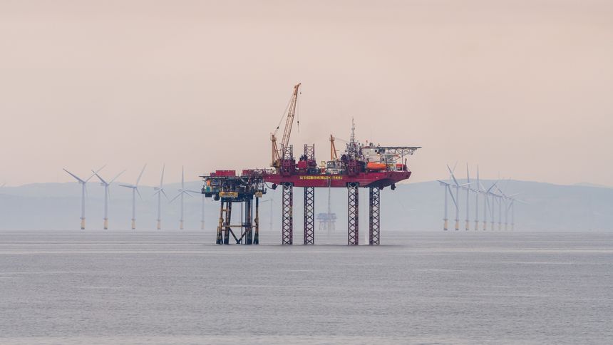 Irish Sea near Merseyside, England, UK - May 17, 2023: An oil rig and wind turbines