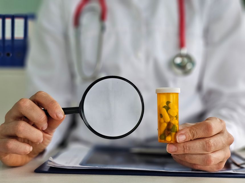 Doctor looks at the pills with a magnifying glass. Drug search