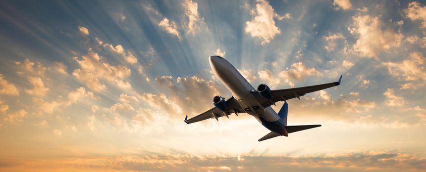 Passenger plane flying in the sky with sunrise or sunset sky in the background. Travelling by air transport