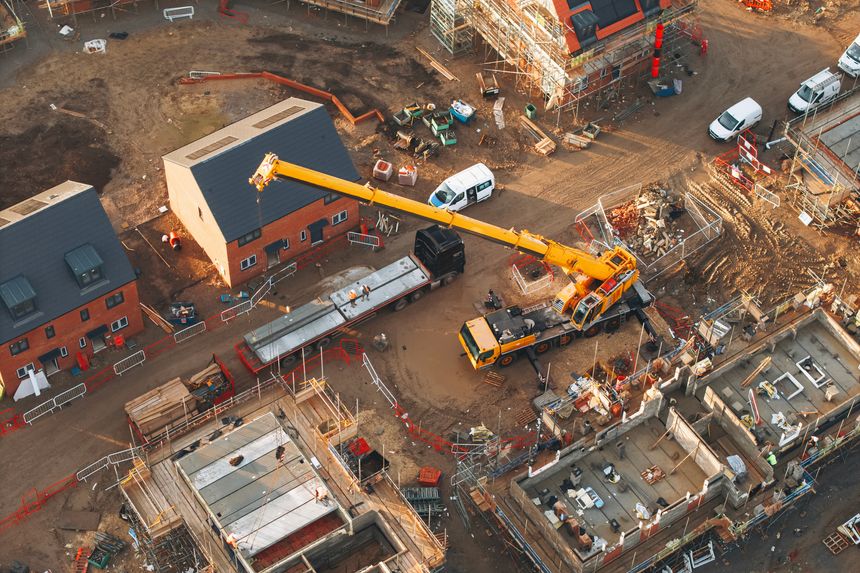 Aerial view of yellow mobile crane at construction site performing lifting operation