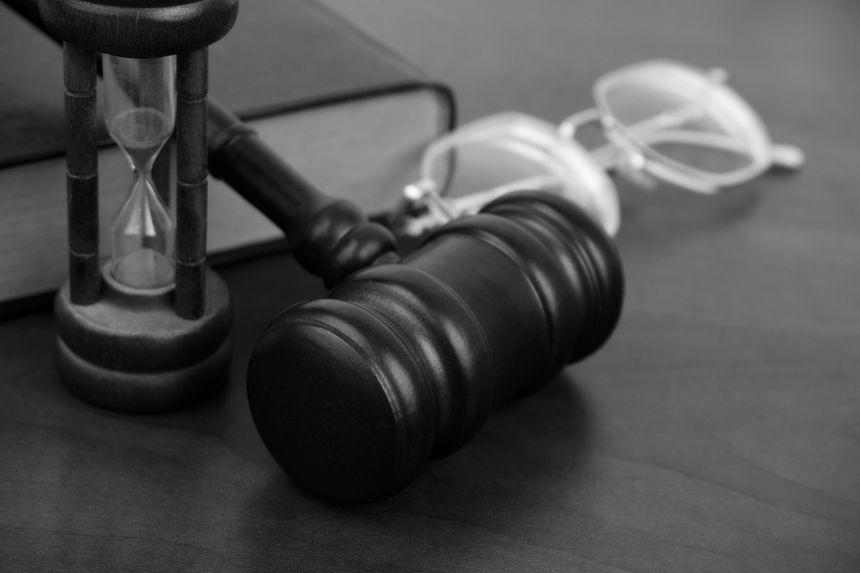 Judge gavel, hourglass, eyeglasses and legal book on table. Legal trial time and justice time concept.