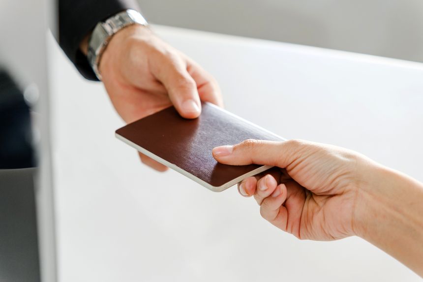 Close-up of a passenger handing a passport to airline ground staff during check-in at airport counter. Highlights global travel, ID verification, and smooth airline boarding process.