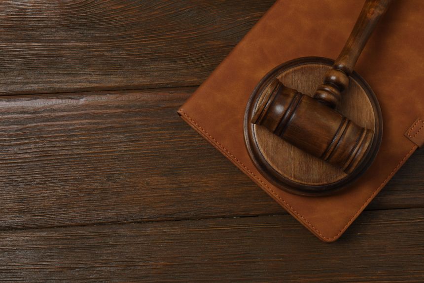 Law concept - open law book, judge's gavel, scales, handcuffs on table in courtroom or law enforcement office. Wooden table, white background.