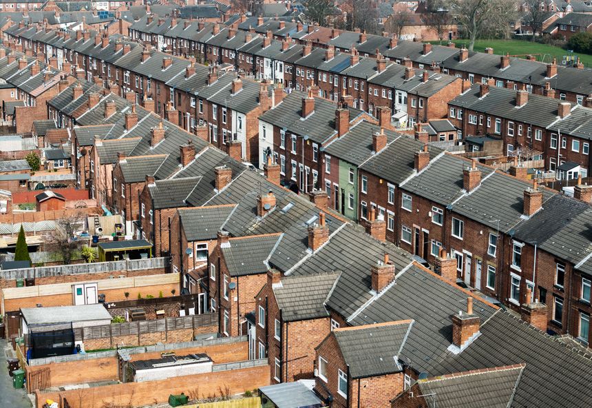 An aerial view above the rooftops of run down back to back terraced houses on a large residential estate in the North of England