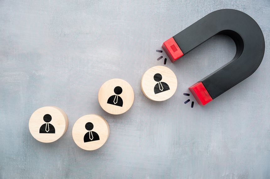 Concept of retention strategy using magnet attracting wooden blocks with businesspeople icons symbolizing keeping valuable customers or employees