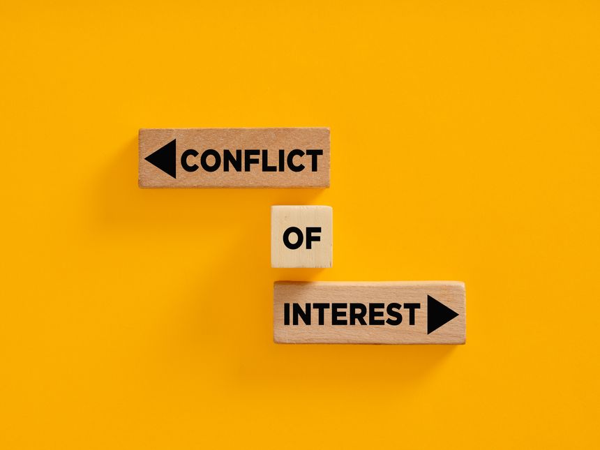 Wooden blocks with conflict of interest concept on yellow background. Conflict of interest in business agreements, deals or partnerships.