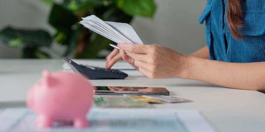 Amidst the organization of monthly bills and expenses, a focus on savings is evident with a piggy bank symbolizing financial goals.