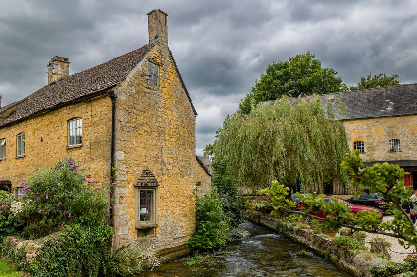 Tourists in the ancient traditional Cotswolds village of Bourton-on-the-Water in summer
