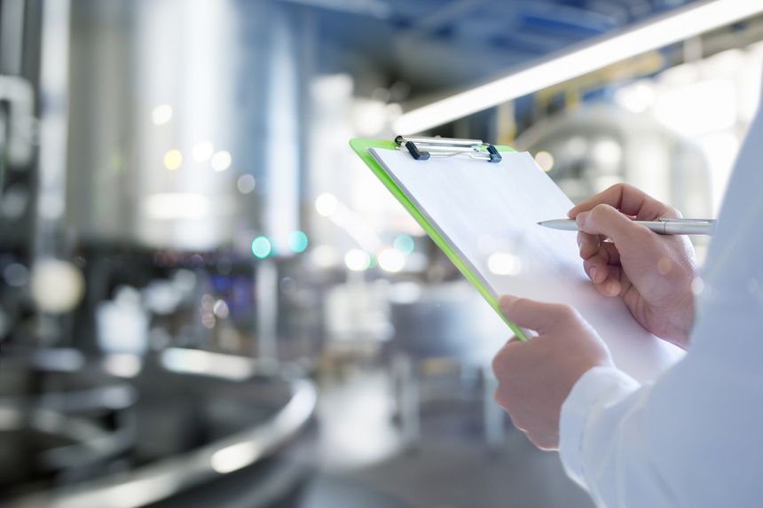 An engineer in a food production facility makes entries in a journal. Work as an engineer in a food company.