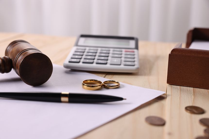 Alimony. Coins, sheet of paper, gavel, pen, rings and calculator on wooden table, closeup
