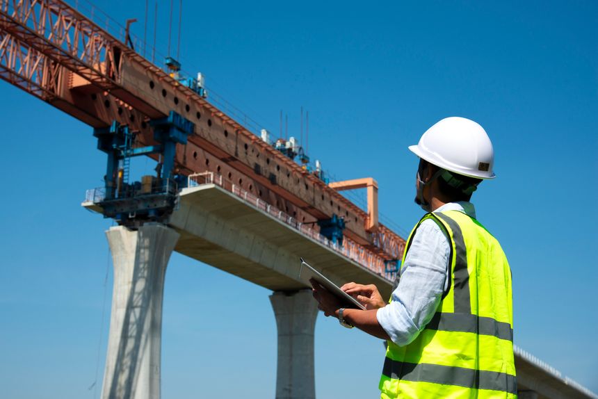Surveyors and civil engineers using a total station and construction blueprints for railway structure infrastructure.