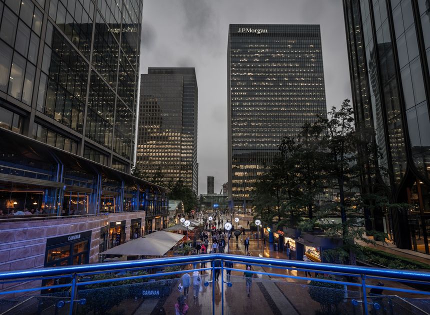 Canary Wharf, London, UK: Reuters Plaza in Canary Wharf with view to the JP Morgan building. Seen from South Colonnade with people walking in the rain.