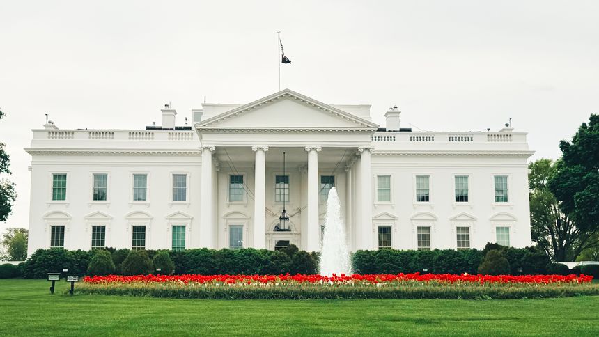 An elegant perspective of the White House set against a backdrop of lush green foliage, with delicate hints of red flowers peeking through. This captivating image highlights the beauty of Washington, D.C.'s iconic landmark, showcasing a harmonious blend of nature and history. Ideal for travel aficionados and those seeking a vibrant yet serene addition to their collection