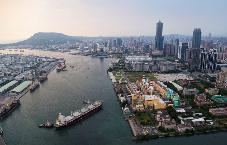 Under the warm glow of the setting sun, Kaohsiung Harbor reveals its vibrant character—an industrial symphony of cargo ships navigating through the busy port, flanked by rows of warehouses and towering cranes. On the right, the city’s skyline rises behind a brightly colored power plant, with the iconic 85 Sky Tower piercing the hazy sky. In the distance, Shoushan (Monkey Mountain) forms a peaceful backdrop, adding a natural contrast to the urban and maritime bustle. This dynamic aerial view captures the energy, scale, and layered beauty of one of Taiwan’s most important port cities.