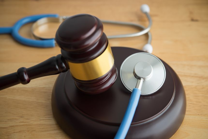 Wood judge hammer gavel and doctor stethoscope on wooden table background in courtroom. Health law, medical law rules, regulations in the health care industry and its patients, medical malpractice concept.