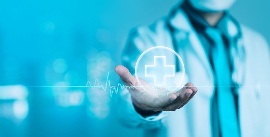 A doctor in a lab coat and mask holds out a hand displaying a glowing medical cross and a pulsating heartbeat line, symbolizing vital signs monitoring, emergency care, and overall health