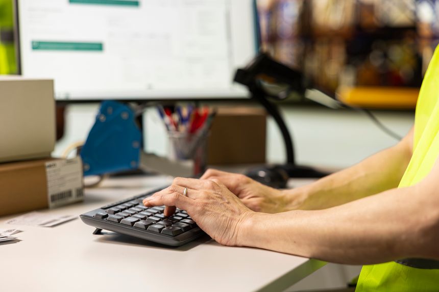 Close up of worker typing shipment details and updating package tracking software, person managing order fulfillment in a distribution center to sort inventory. Online shopping logistics.