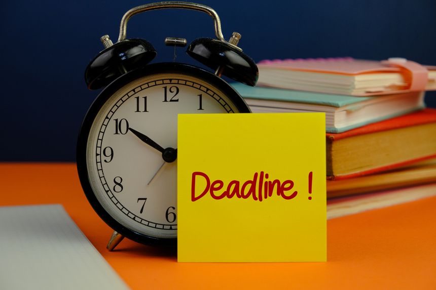 a notepad paste on the alarm clock with text of deadline on dark background as a memo or message concept.