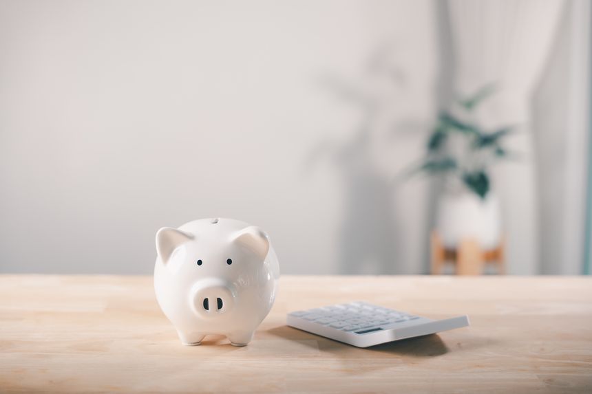 Bank money piggy save tax plan saving retirement financial invest sits on wooden desk top beside modern calculator used for tracking personal income concept planning budget goals.