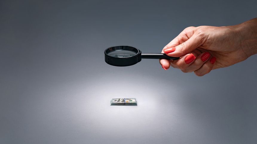 Visual of financial audit using magnifying glass to check expenses and income.