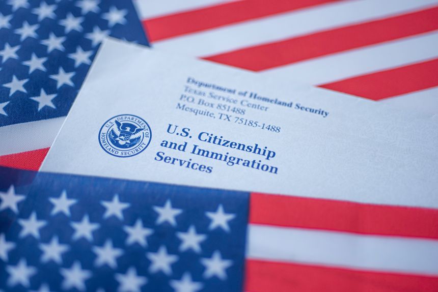 Washington, DC, USA - September, 16, 2019: Letter (Envelope) from USCIS covered in flag of USA on American colors background.