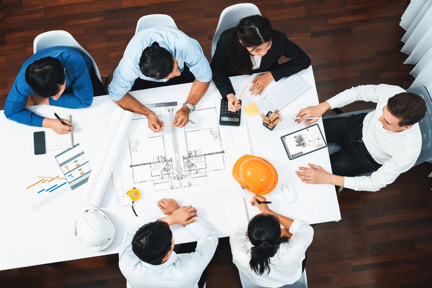 Top view banner of diverse group of civil engineer and client working together on architectural project, reviewing construction plan and building blueprint at meeting table. Prudent