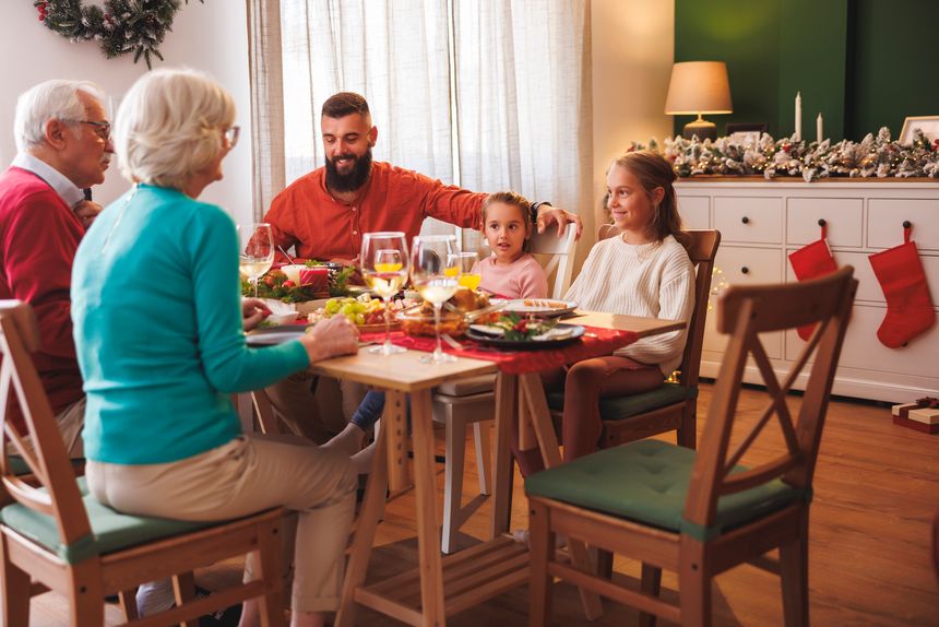 Happy multi-generation family gathered around the table, having Christmas dinner all together at home