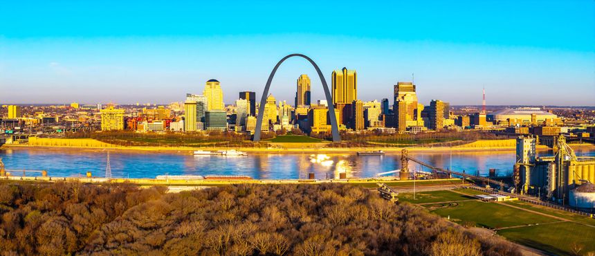 Aerial panoramic view of Gateway Arch and St Louis skyline glowing in golden sunset light