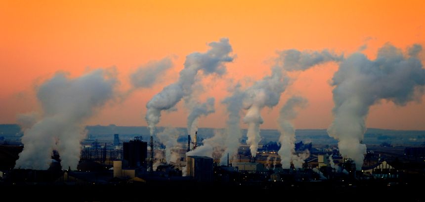 Factory smoke rising in air pollution at sunrise of sunset