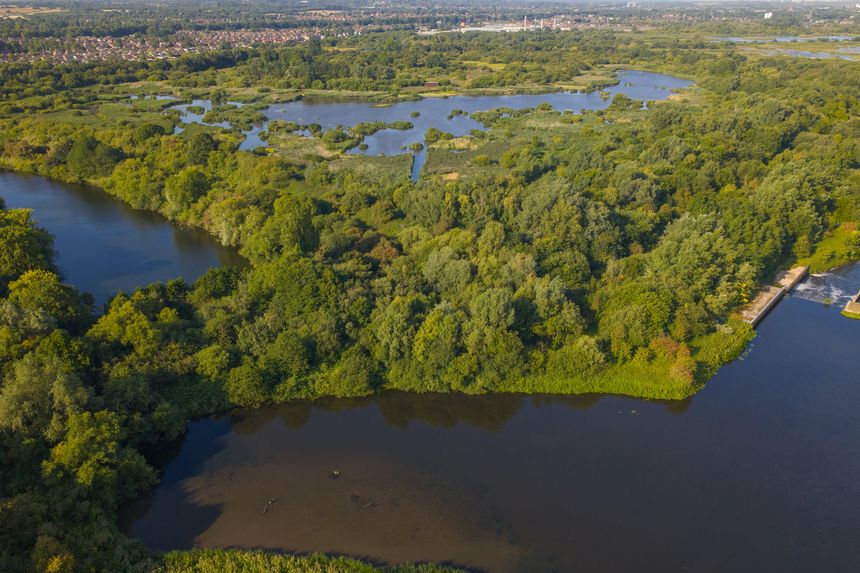 Aerial view of the River Mersey and surrounding wetlands near Woolston in Warrington, showcasing lush green woodlands