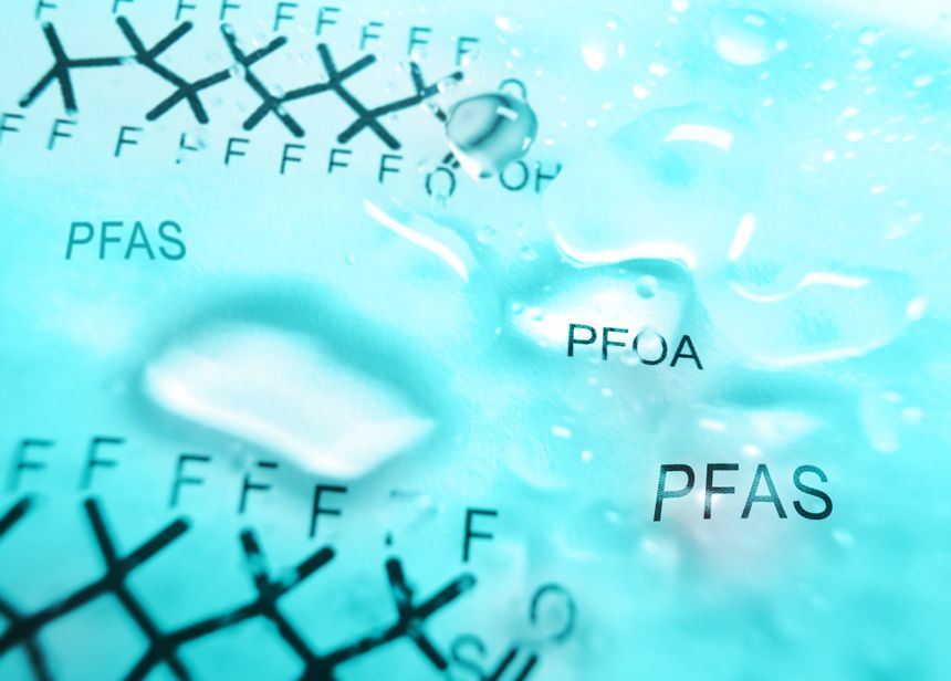 Water droplets with  PFAS text and  chemical structure in the background -- contaminated drinking water concept