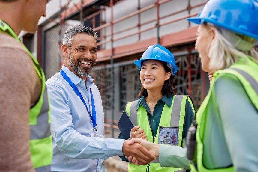 Smiling construction professionals exchanging a handshake as part of their partnership on site. Happy engineer shaking hands at construction site with happy businessman. Handshake between middle eastern construction manager with architect at building site, conclude an agreement.