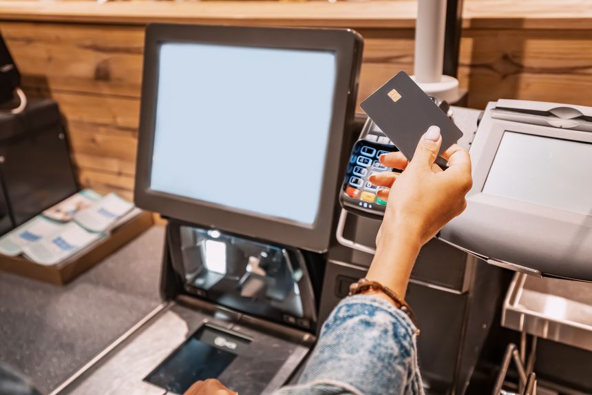 The girl buyer applies a credit card to the pos terminal to pay for purchases at the self-service checkout
