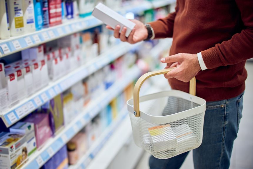 A man selecting products in a pharmacy aisle, focusing on health and wellness items.
