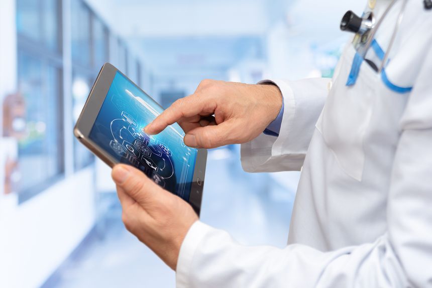 A healthcare professional examines information on a digital tablet in a bright, high-tech medical facility, focusing on patient data analysis.