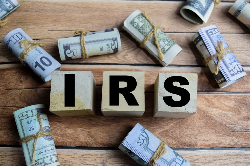 Concept word IRS - Internal Revenue Services on a wooden table with dollar bills