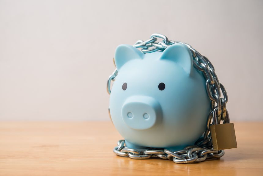 Blue piggy bank locked with chain and padlock on wooden table white wall background. Savings money protection, money management, scammer prevention, safety deposit account, financial, economy concept.