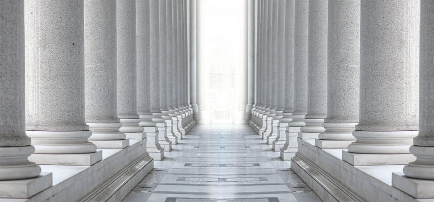 Two rows of white marble columns. Hallway with white pillars. Bright light between two rows of columns