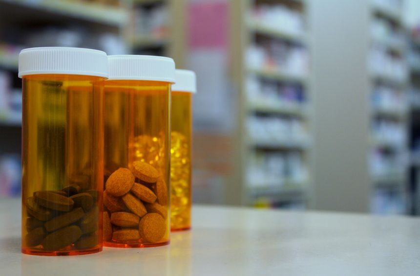 Pill bottles sit on top of a pharmacy counter in the dispensary.