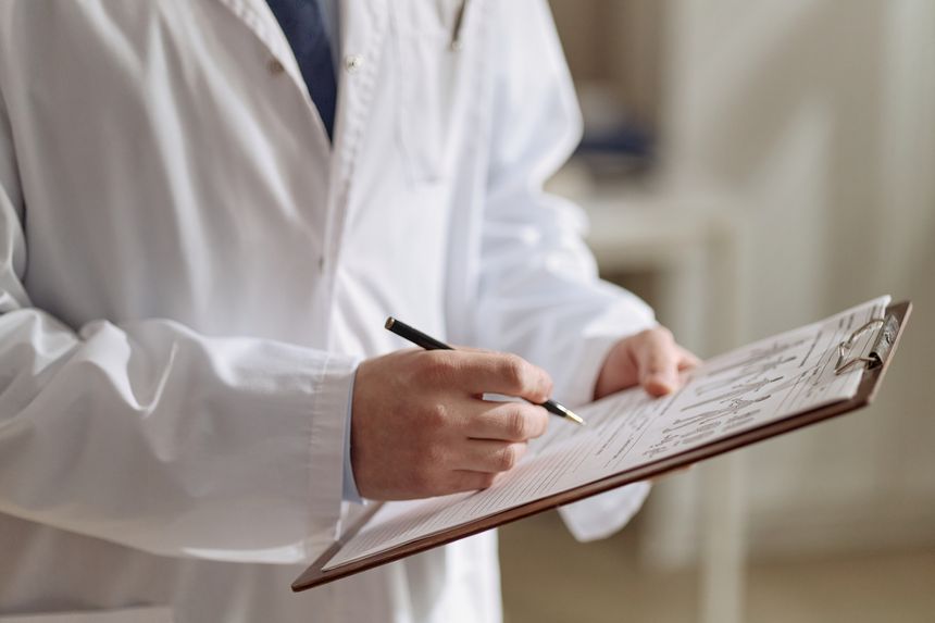Close up of doctor holding clipboard and writing medical notes during patient assessment. Suitable for healthcare marketing, insurance, diagnosis, treatment, or clinic services