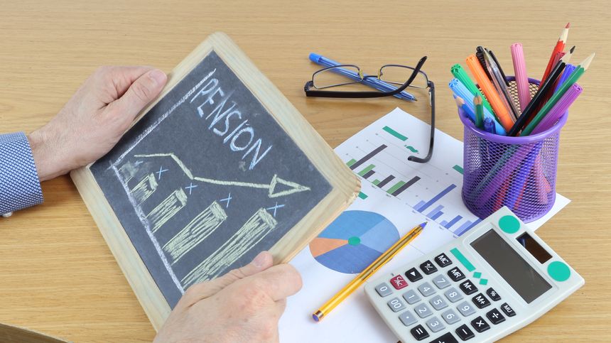 A man's hands hold a blackboard with the word PENSION written on it, a concept of calculation based on contributions paid.
