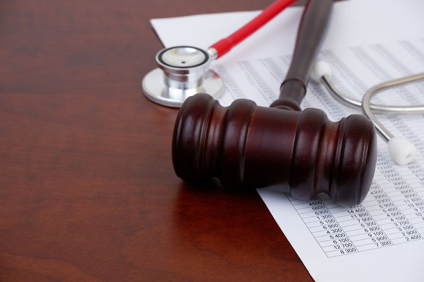 Judge gavel, stethoscope and financial document on table.