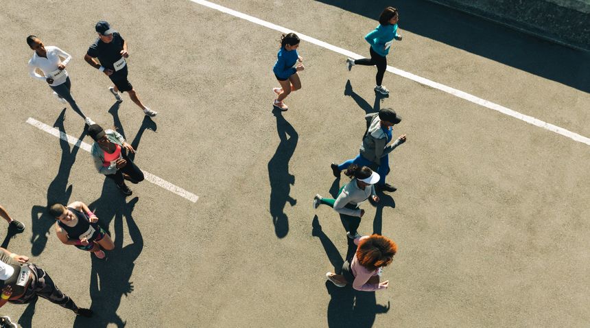 A diverse group of people participate in an outdoor race, showcasing energy and community spirit. Captured from above, the image highlights movement, unity, and fitness.