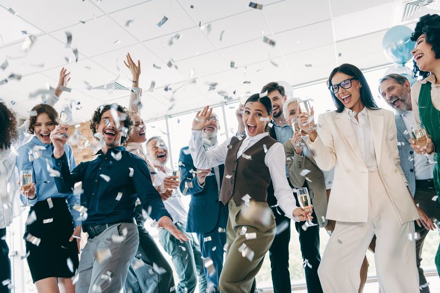 A joyful team of diverse professionals gathered in an office environment, celebrating success with confetti and bright smiles, showcasing camaraderie and teamwork.