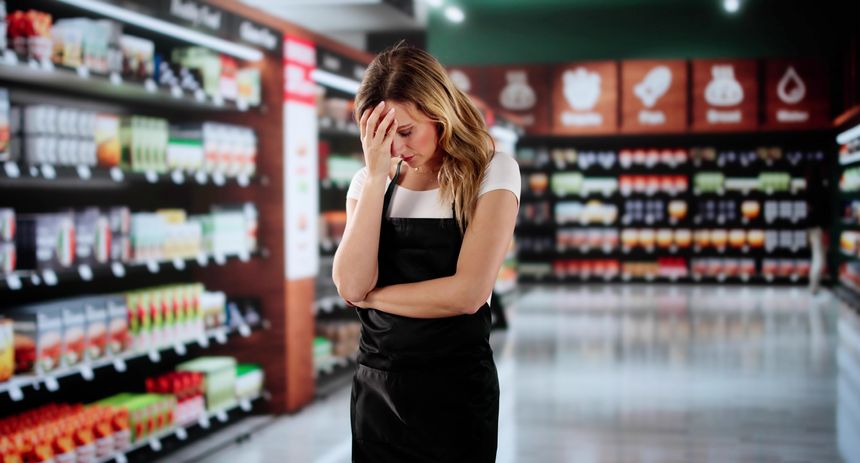 Exhausted Young Woman Struggles To Keep Up With Supermarket Stock.