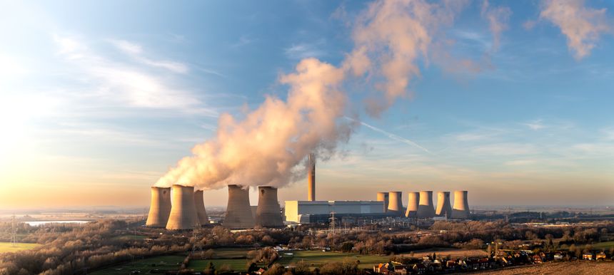 Aerial panoramic landscape of a large coal fired power station in UK at sunset with coal stack and cooling towers in countryside